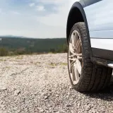 Opony wielosezonowe na szutrowej drodze, w tle krajobraz. Zastanawiasz się, ile wytrzymują opony wielosezonowe?