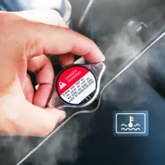 Dłoń dotyka korka chłodnicy, z którego wydobywa się para. Widoczny symbol ostrzegawczy i napis "DANGER WARNING". Sygnalizuje to prawdopodobnie **mało płynu w chłodnicy**.