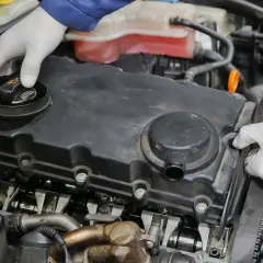 Mechanik w białych rękawiczkach sprawdza silnik. Czy to odma w samochodzie? To ważny element układu.