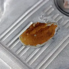 Fragment metalowej obudowy, prawdopodobnie lekko przytarty silnik, z widocznym fragmentem rdzy lub nalotu.