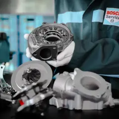 Mechanik w rękawiczkach prezentuje części turbosprężarki, kluczowego elementu, gdzie jest turbina w samochodzie, zwiększającego moc silnika.