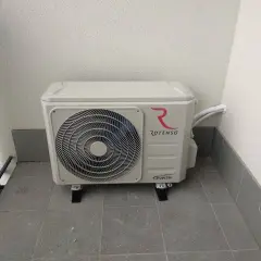 Jednostka zewnętrzna klimatyzacji Rotenso z logo, zamontowana na balkonie. Złącze klimatyzacji jest widoczne po prawej stronie.
