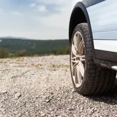 Opony wielosezonowe na szutrowej drodze, w tle krajobraz. Zastanawiasz się, ile wytrzymują opony wielosezonowe?