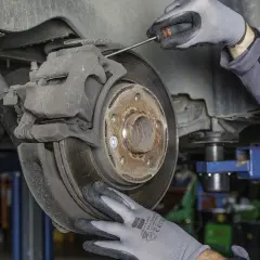 Mechanik sprawdza zużyte klocki hamulcowe. Objawy zużycia mogą być groźne.