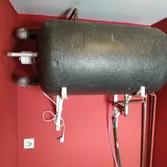 Cieknący zawór bezpieczeństwa przy bojlerze, podłączony do węża odprowadzającego wodę.