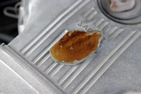 Fragment metalowej obudowy, prawdopodobnie lekko przytarty silnik, z widocznym fragmentem rdzy lub nalotu.
