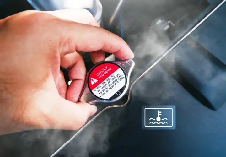 Dłoń dotyka korka chłodnicy, z którego wydobywa się para. Widoczny symbol ostrzegawczy i napis "DANGER WARNING". Sygnalizuje to prawdopodobnie **mało płynu w chłodnicy**.