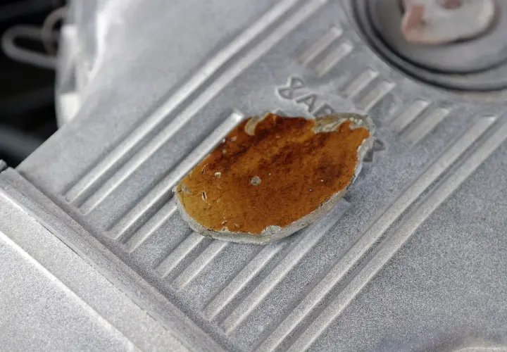 Fragment metalowej obudowy, prawdopodobnie lekko przytarty silnik, z widocznym fragmentem rdzy lub nalotu.