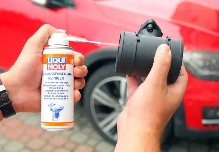 Czyszczenie przepływomierza: ręka trzyma puszkę preparatu Liqui Moly i aplikuje go na element.