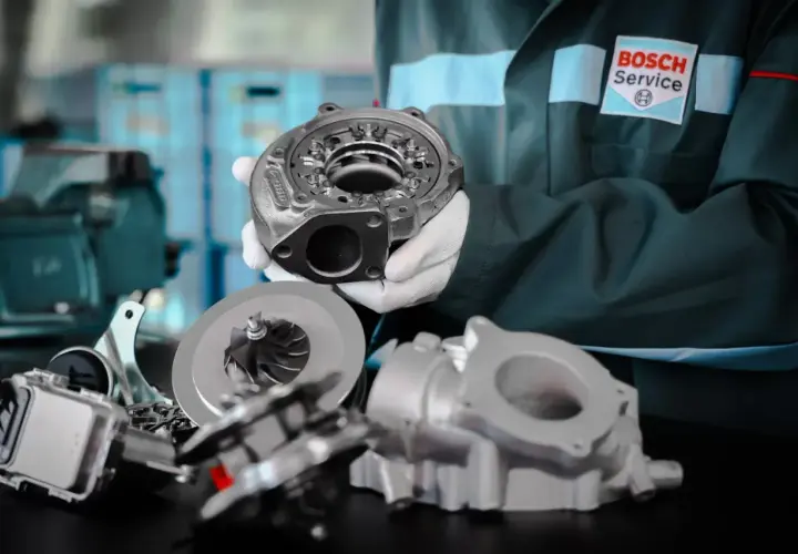 Mechanik w rękawiczkach prezentuje części turbosprężarki, kluczowego elementu, gdzie jest turbina w samochodzie, zwiększającego moc silnika.