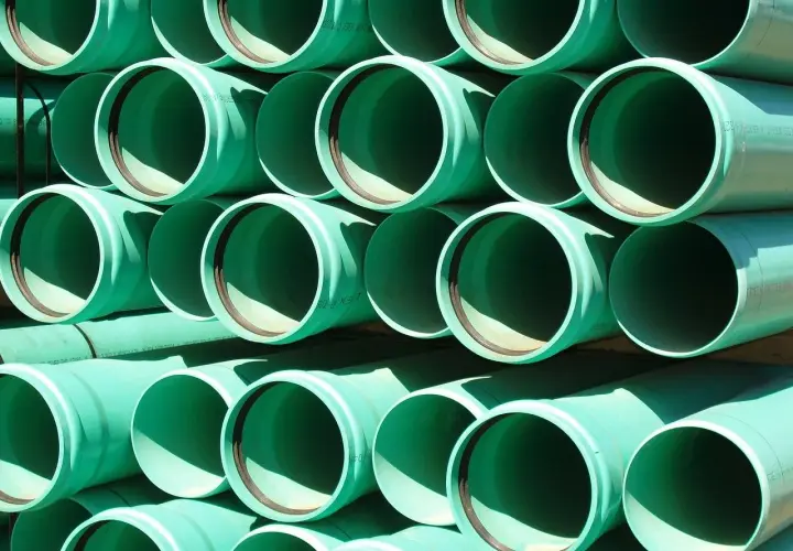 Zielone rury PVC ułożone w stosy, gotowe do tworzenia systemów łączenia rur wodnych.