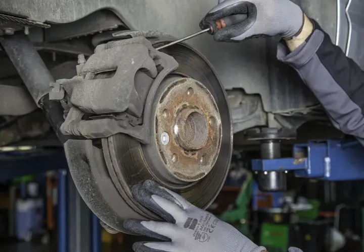 Mechanik sprawdza zużyte klocki hamulcowe. Objawy zużycia mogą być groźne.