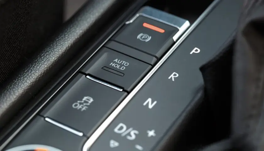 Przycisk AUTO HOLD w samochodzie. Ułatwia postój, zapobiegając stoczeniu się pojazdu.