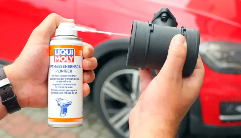 Czyszczenie przepływomierza: ręka trzyma puszkę preparatu Liqui Moly i aplikuje go na element.