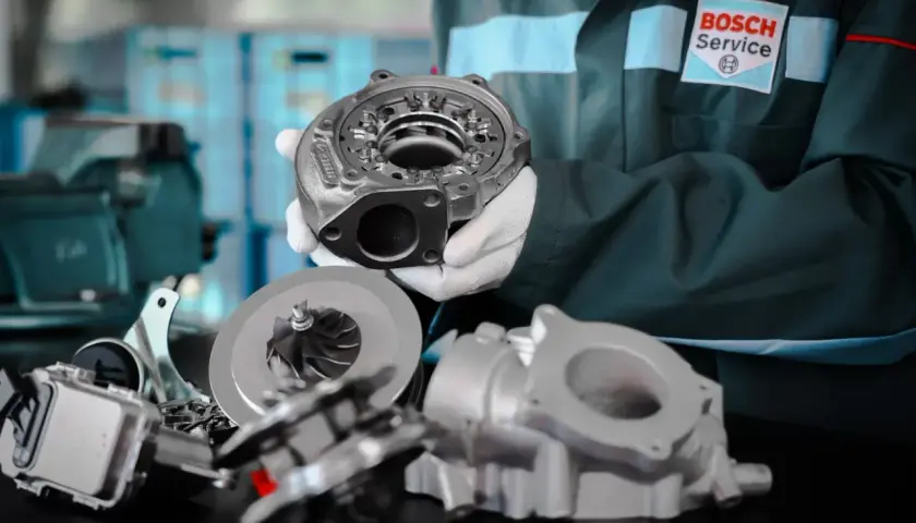 Mechanik w rękawiczkach prezentuje części turbosprężarki, kluczowego elementu, gdzie jest turbina w samochodzie, zwiększającego moc silnika.