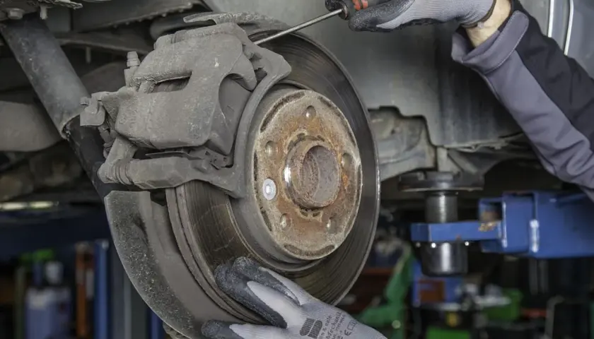 Mechanik sprawdza zużyte klocki hamulcowe. Objawy zużycia mogą być groźne.