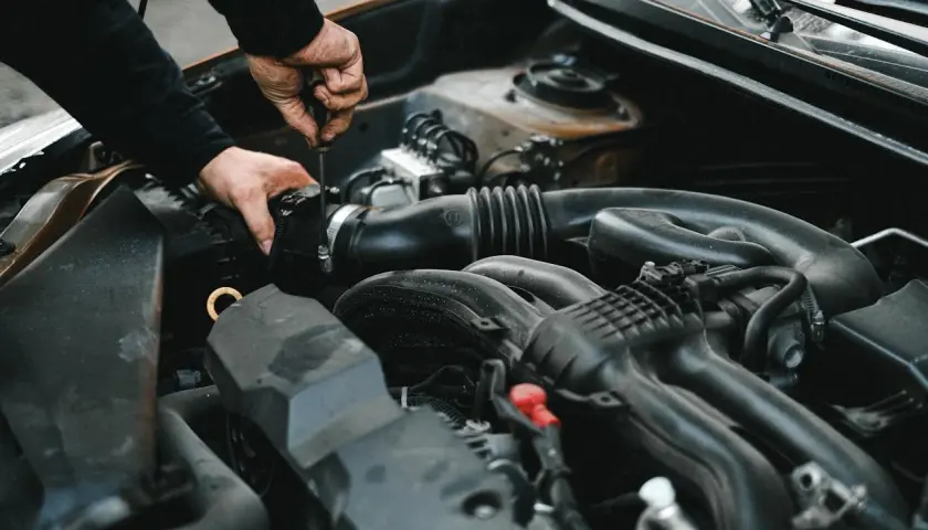 Mechanik dokręca śrubę przy silniku. Może to być związane z uszkodzonym przekaźnikiem pompy paliwa objawy, które utrudniają pracę auta.