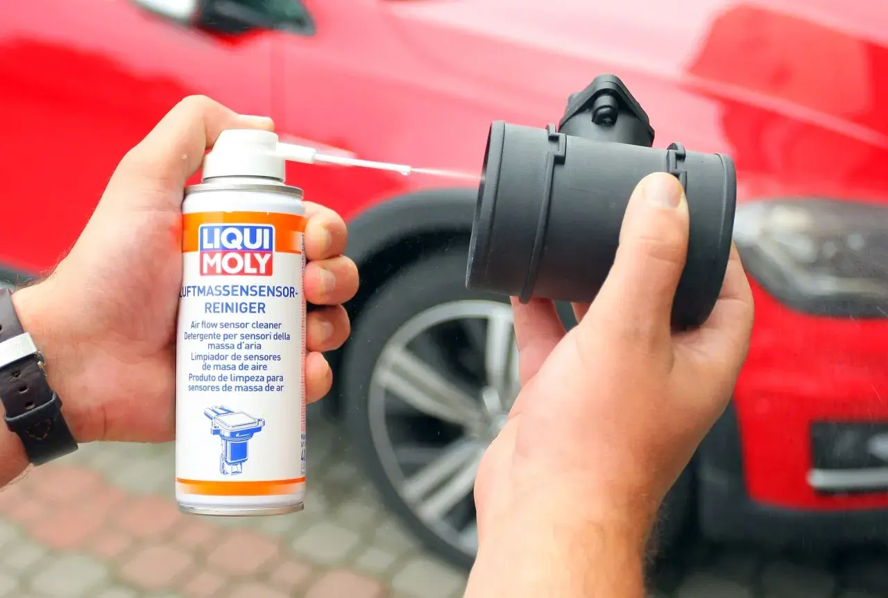 Czyszczenie przepływomierza: ręka trzyma puszkę preparatu Liqui Moly i aplikuje go na element.