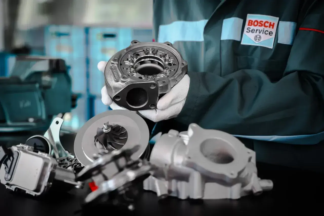 Mechanik w rękawiczkach prezentuje części turbosprężarki, kluczowego elementu, gdzie jest turbina w samochodzie, zwiększającego moc silnika.
