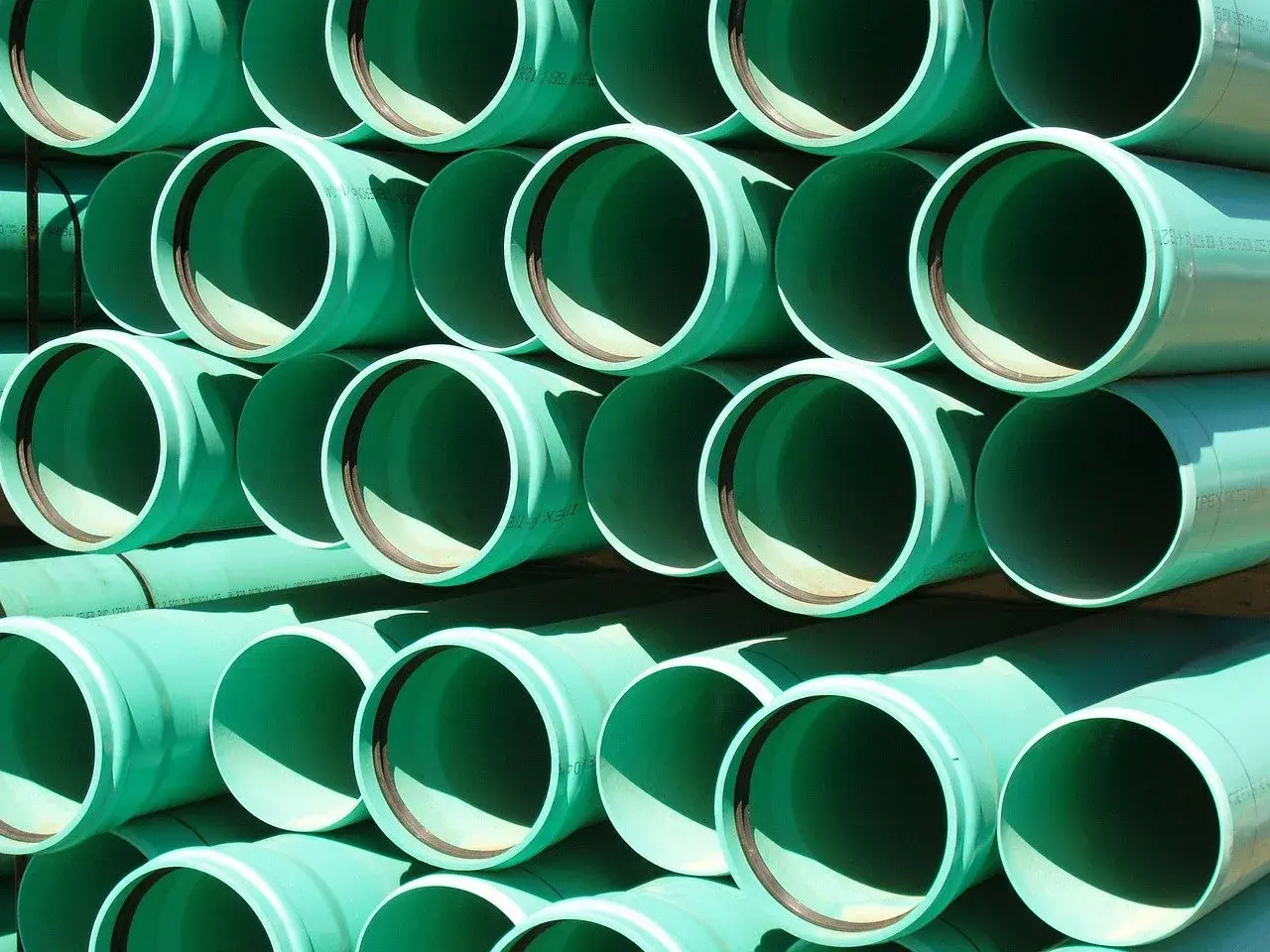 Zielone rury PVC ułożone w stosy, gotowe do tworzenia systemów łączenia rur wodnych.