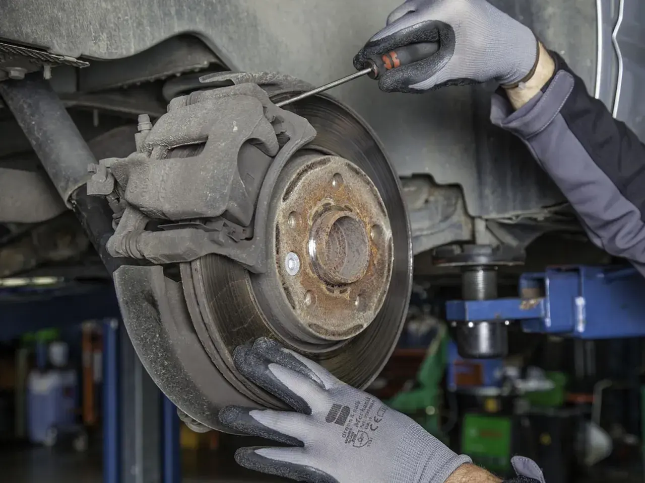 Mechanik sprawdza zużyte klocki hamulcowe. Objawy zużycia mogą być groźne.