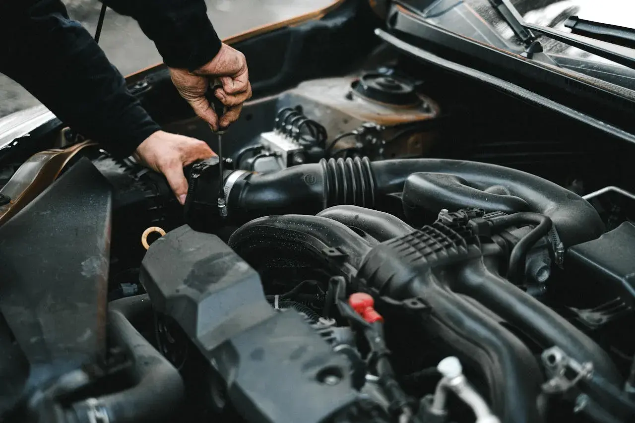 Mechanik dokręca śrubę przy silniku. Może to być związane z uszkodzonym przekaźnikiem pompy paliwa objawy, które utrudniają pracę auta.