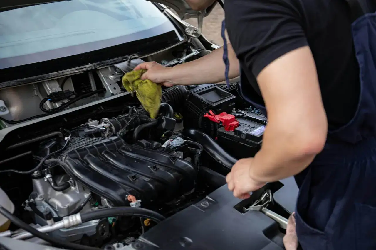 Mechanik czyści silnik samochodu. Pytanie: czym wyczyścić przepływomierz? Użyj delikatnej ściereczki i specjalnego preparatu.