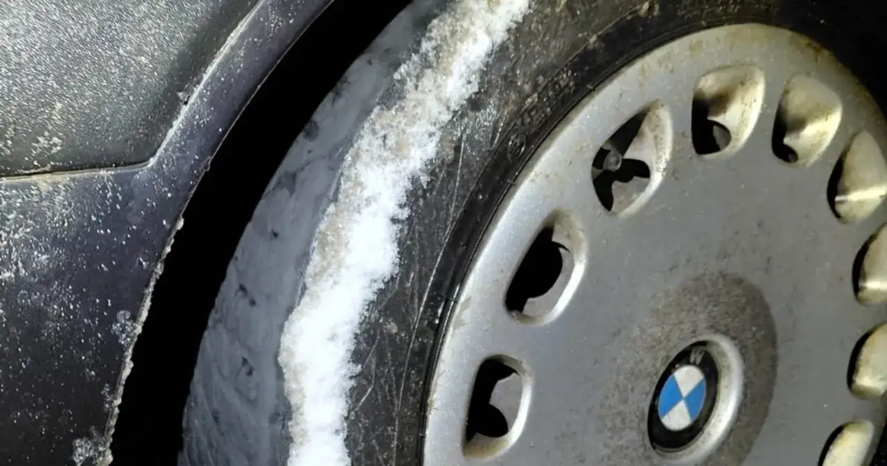 Opona BMW z widocznym bieżnikiem pokrytym śniegiem. Grozi mandat za łyse opony, gdy bieżnik jest zużyty i nie zapewnia przyczepności na śliskiej nawierzchni.