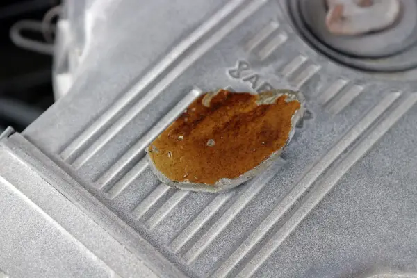 Fragment metalowej obudowy, prawdopodobnie lekko przytarty silnik, z widocznym fragmentem rdzy lub nalotu.